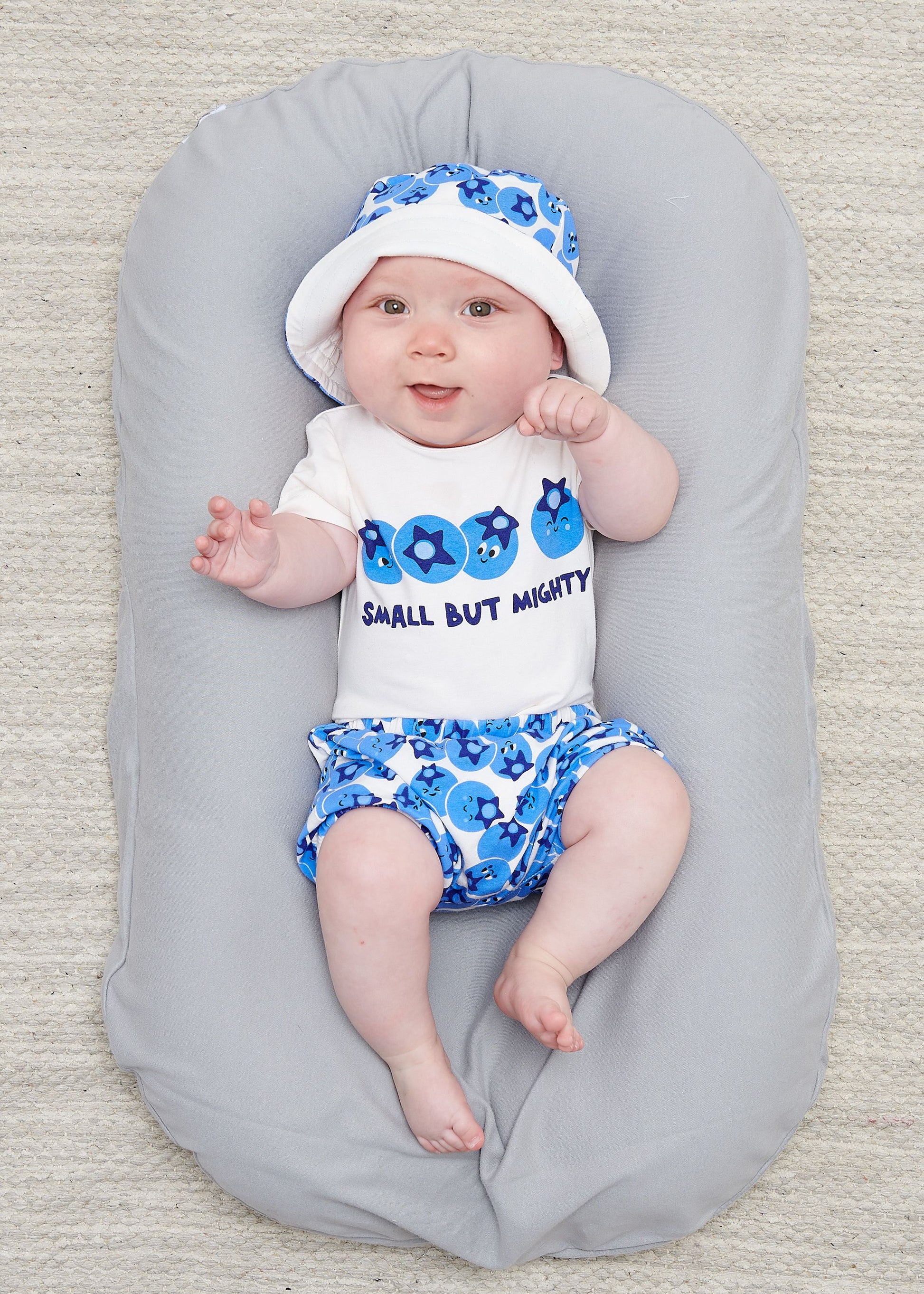 baby wearing blueberry print bloomers and sun hat with coordinating blueberry bodysuit