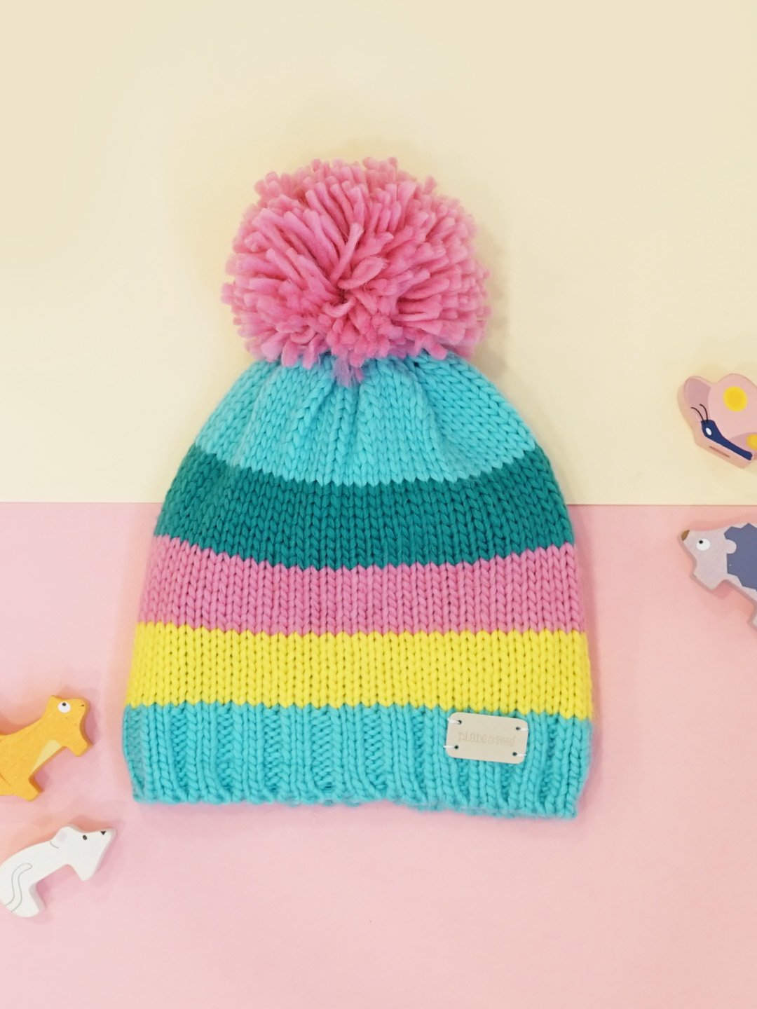 turquoise, teal, yellow and pink knitted hat with a pom pom on top