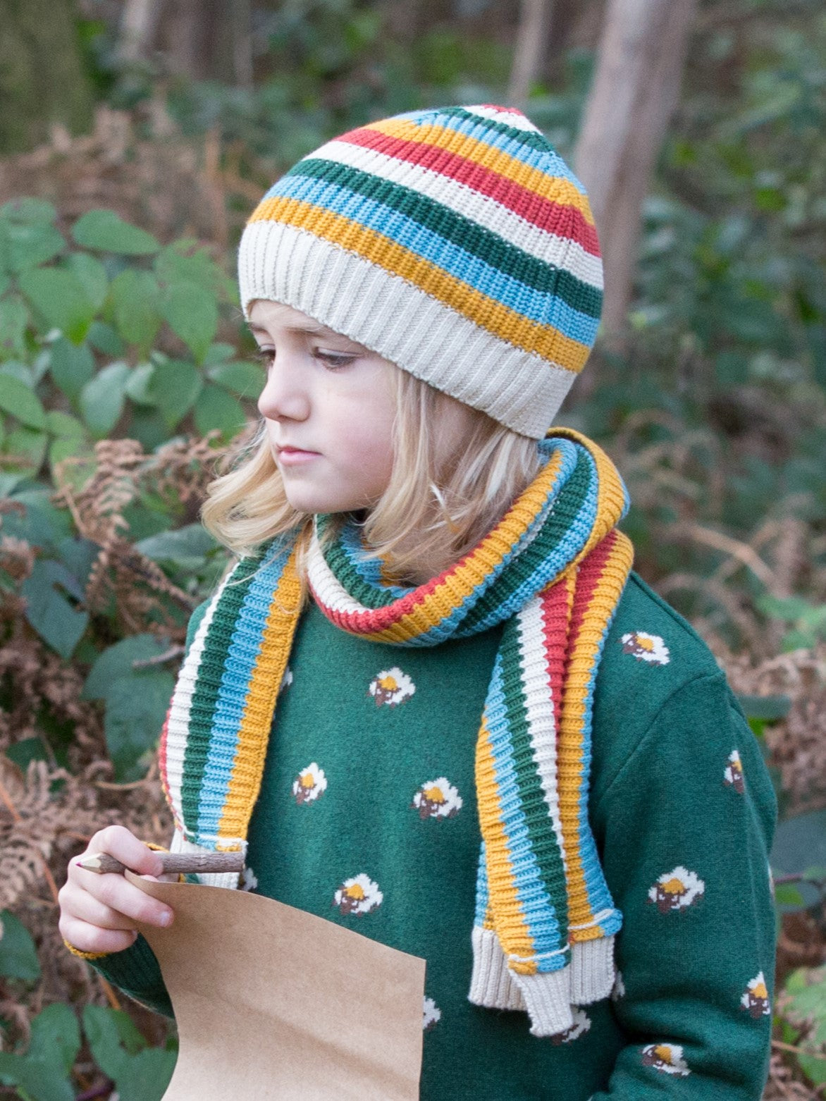child wearing little green radicals rainbow striped hat and scarf