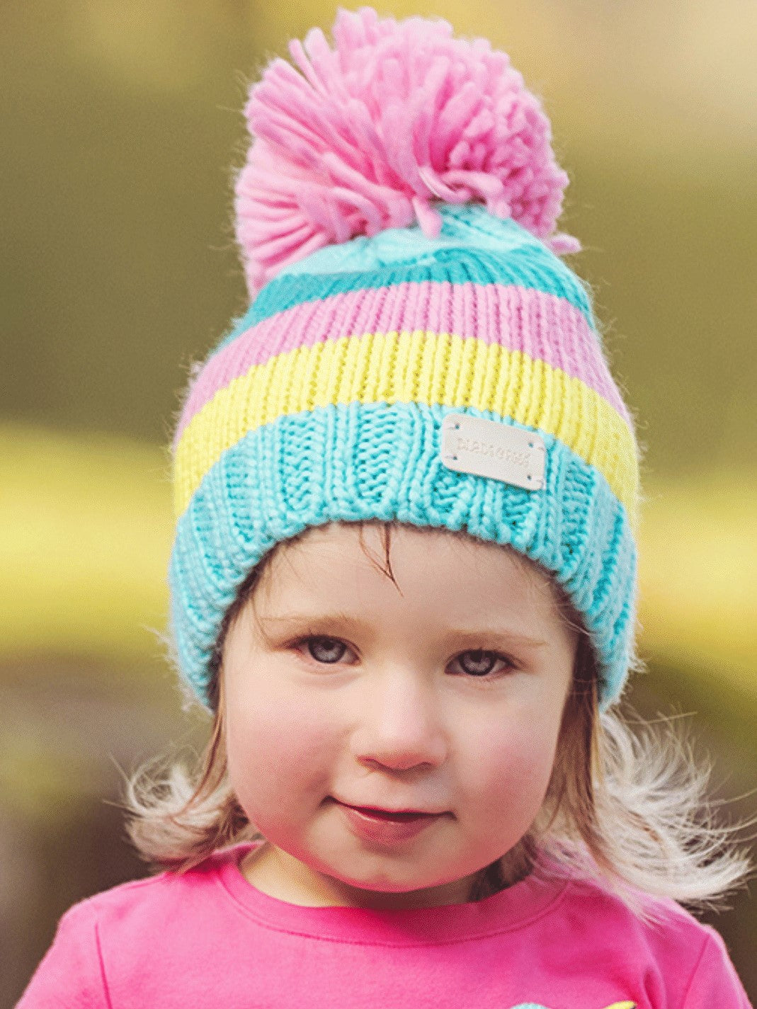 turquoise, teal, yellow and pink knitted hat with a pom pom on top